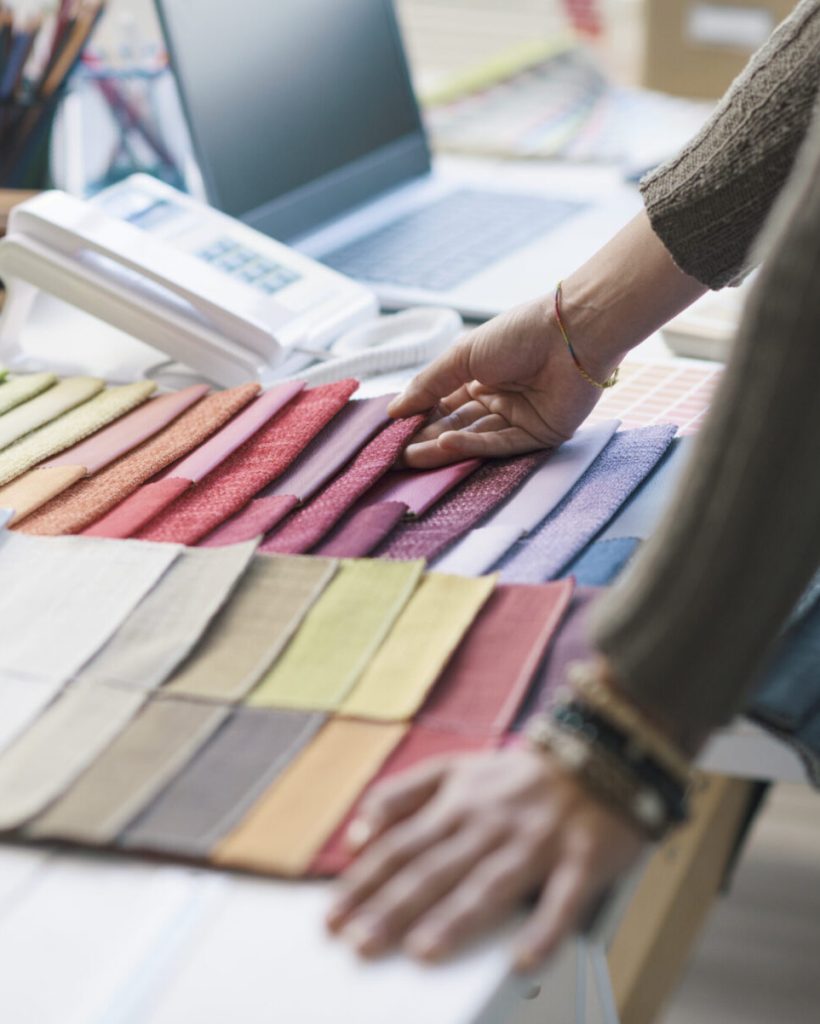 Professional decorator working in her studio, she is choosing fabric swatches for her project